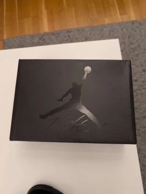 Svarta Air Jordan 4 Retro sneakers - Säljer ett par helsvarta Air Jordan 4 Retro sneakers med klassisk meshpanel, mockadetaljer och synlig Air-sula. Skorna har högt skaft och ikoniska Jumpman-loggan på plösen. Perfekta för dig som gillar streetwear och vill ha en tidlös look.