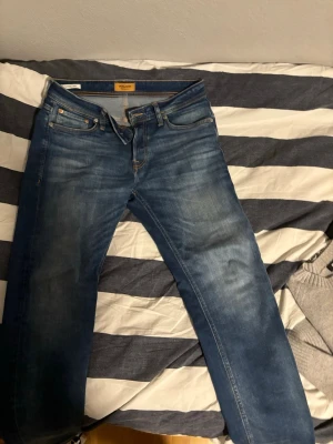 Blå jeans från Jack & Jones - Snygga blå jeans från Jack & Jones med klassisk femficksmodell och normal passform. Jeansen har en lätt tvättad look och detaljer i kontrastsömmar. Perfekta till en avslappnad stil och tillverkade i bomull.