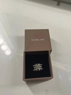 Silverfärgad ring från Edblad - Säljer en cool och chunky silverfärgad ring från Edblad. Ringen har ett unikt geometriskt mönster med flera små trianglar som bildar en modern och edgy look. Perfekt för dig som vill sticka ut med dina accessoarer.