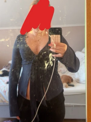 Marinblå topp med knyt framtill - Trendig marinblå knyttopp med långa ärmar och djup v-ringning. Toppen har ett snyggt knyt framtill som ger en feminin siluett. 