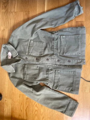 Olivgrön jeansjacka  - Säljer olivgrön jeansjacka från Nelly! Använd 1 gång. Säljer pga av att den är förliten.  Dragsko i midjan för en mer markerad siluett. 💚Storlek: XS men stor så skulle säga S/ liten M i storlek. Modellen är längre än ” vanliga jeansjackor”. Nypris 600 kr. 