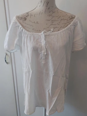 Vit tunn kortärmad top - Vit tunn kortärmad top med 4 knappar och snöre.