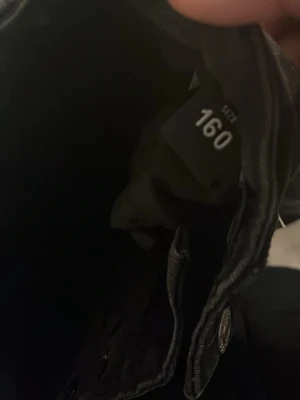 Svarta jeansshorts med bakfickor - Säljer ett par svarta jeansshorts med två bakfickor och bälteshällor. Klassisk femficksmodell med normal passform och raka ben. Perfekta till sommaren och enkla att matcha med olika stilar.