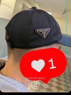 Svart keps från Prada - Snygg svart keps från Prada med det klassiska trekantiga metallmärket på sidan.                                  PRISET GÅR O DISKUTERAS!