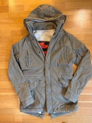 Olivgrön parkas från Superdry - Superdry parka, dragkedjan behöver bytas. Det går dock att använda den ändå med knappar.