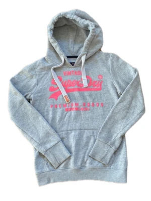 Superdry hoodie S - Säljer denna feta Superdry hoodie, superfräsh och passar alla outfits🔥🔥Grå modell med rosa text som ger en snygg kontrast🌸 Inga defekter - inga hål, inga fläckar eller dålig lukt🌟Storlek S
