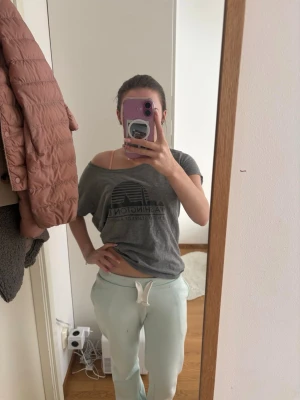 Grå t-shirt med Washington DC-tryck - Snygg grå t-shirt med svart tryck av Washington DC och siluett av staden. T-shirten har korta ärmar och en avslappnad, loose passform med bred halsringning som kan bäras offshoulder. Perfekt för en chill och urban stil.