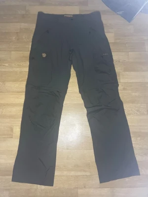 Svarta cargobyxor från Fjällräven - Säljer ett par svarta byxor från Fjällräven. Dem är Storlek 48 är inte riktigt säker på vilken storlek det motsvarar, Dem är såklart äkta! Säljer dessa för 449:- skriv vid frågor:) skickar samma dag!
