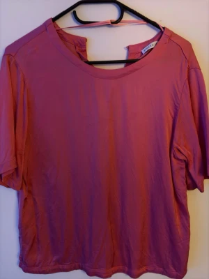 Rosa blus - En blus med rund halsringning och korta ärmar. Blusen har en loose passform.