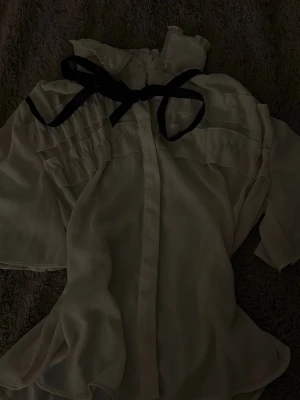 Vit blus med volanger och svart rosett - Jätte fin tunn blur från Zara. Med pärl detalj och snöre som man kan knyta och ta bort som man vill, verkligen Blair Walldorf känsla. En liten ljus fläck uppe vid halsen som knappast syns, går o se på bild 3💕