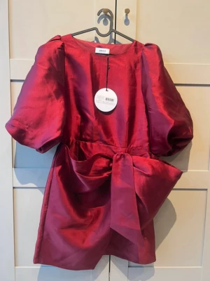 Vinröd kort klänning med puffärm - röd kort klänning från Joelle med stora puffärmar och en stor rosett i midjan. 1000kr nypris 