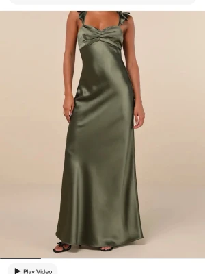 Grön långklänning i satin med snörning - Stilren långklänning i olivgrön satin med smala axelband och öppen rygg med snygg snörningsdetalj. Klänningen har en elegant, figurnära passform och faller mjukt längs kroppen. Helt ny med prislappen kvar. Säljer den pga att jag skulle ha den på balen men har nu ångrat mig👏🏻🫶🏻