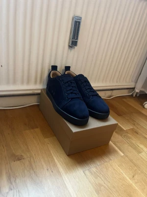 Mörkblå loubitins med svart sula - Snygga mörkblå sneakers i mocka med svart sula och matchande mörkblå skosnören. Låg modell med stilren design och diskreta detaljer. Insidan är ljusbeige för en schysst kontrast. Perfekta för dig som gillar minimalistisk och clean stil.