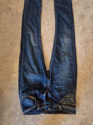Blå raka jeans från Denim Co. - Säljer ett par klassiska blå jeans från Denim Co. Jeansen har rak passform, fem fickor och snygga slitningar för en avslappnad look. Tillverkade i bomull med en tidlös tvätt och kontrastsömmar. Perfekta till en casual outfit. Pruta gärna