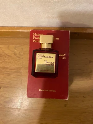 Maison Francis Kurkdjian Baccarat Rouge 540 - Exklusiv parfymflaska i röd glas med elegant guldigt lock från Maison Francis Kurkdjian. Baccarat Rouge 540 Extrait de Parfum har en lyxig och modern design med tydliga linjer och en guldplatta på framsidan. Perfekt för dig som vill ha något unikt och stilfullt.