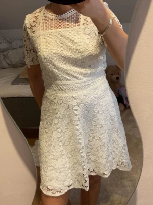 Vit spetsklänning - Superfin vit klänning i spets med korta ärmar och rund hals. Klänningen har ett vackert blommigt spetsmönster. Perfekt för studenten eller andra speciella tillfällen. Hör av er vid frågor🤍