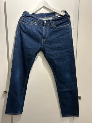 Mörkblå Evisu jeans med broderade fickor - Unika mörkblå jeans från Evisu med raka ben och snygga broderier på bakfickorna. Ena fickan har ett färgglatt motiv och den andra ett stilrent mönster. Klassisk femficksmodell i denim med läderpatch i midjan.