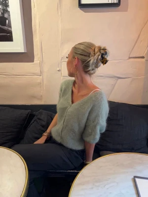 Ljusgrön fluffig stickad kofta - Supermjuk och fluffig ljusgrön stickad kofta med kort ärm och v-ringning. Säljer den pga att jag inte använder den och den bara tar upp plats i min garderob🤗 Andvänd EN gång och inget tecken på användning🥰super fin till en somrig outfit☀️Pris kan diskuteras!!