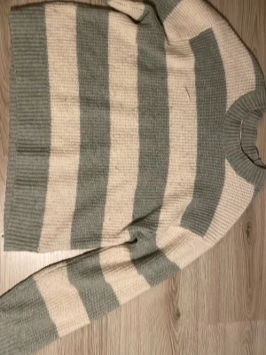 Randig stickad tröja i grön och vit - Fin stickad tröja med ränder i grön och vit. Tyget är ribbat.
