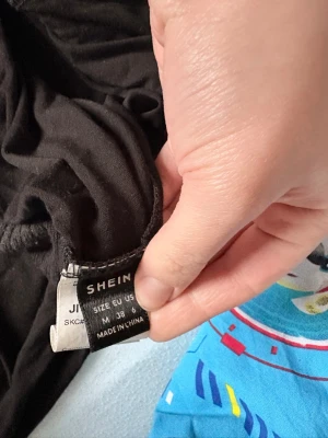 Svarta leggings från SHEIN - Säljer ett par svarta leggings från SHEIN i storlek M (EU 38). De är stretchiga och har en enkel. Materialet är mjukt och bekvämt. Det finns en liten orange prickdetalj på ena benet
