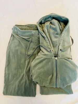 Grönt velourset från Gina Tricot S/XS - Mysigt loungewear-set i ljusgrön velour från Gina Tricot. Setet består av en ziphoodie med dragsko i huvan och matchande byxor med resår och dragsko i midjan. Perfekt för chill dagar hemma eller när du vill vara extra bekväm. Använt 2 gånger. 