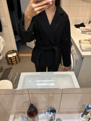 Svart kappa med knyte  - Säljer denna jättefina kappan ifrån Gina tricot för att den är lite liten på mig. Jag köpte den hösten 2023 och har använts flitigt men tagits hand om väl. Den är lite nopprig men inget som känns eller syns om man inte kollar på nära håll❣️köpt för 700 ungefär