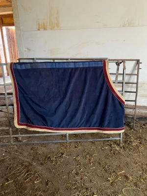 Jacson fleecetäcke till häst - Mörkblått fleecetäcke från Jacson Rug Collection med bred röd och beige kant. Täcket är rektangulärt och passar till häst, perfekt för att hålla värmen i stallet eller efter träning. Materialet är mjukt fleece och täcket har en klassisk design. Utan mag gjordar, strl 115