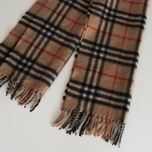 Burberry Scarf | Haldsduk - Klassisk burberry halsduk i det ikoniska rutiga mönstret. Halsduken har fransar i ändarna och är tillverkad i mjukt material som känns skönt mot huden. Perfekt accessoar för att lyfta din outfit med en tidlös look. Produkten har ett litet hål som syns på sista bilden.