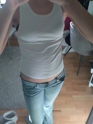 Vit ribbad linnetopp - Säljer en enkel och stilren vit ribbad linnetopp med rund halsringning. Toppen är ärmlös och har en tight passform som sitter snyggt på kroppen. Perfekt att matcha med jeans eller kjol för en clean look.