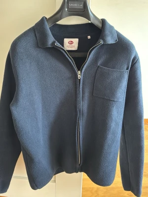 Mörkblå ziptröja från Petrol - Mörkblå ziptröja från Petrol med krage och bröstficka. Tröjan är stickad och har en hel dragkedja framtill. Perfekt för lager på lager och enkel att matcha med olika outfits.