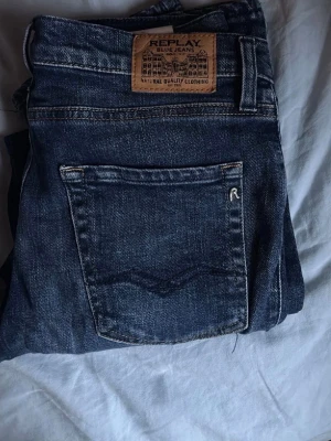 Mörkblå jeans från Replay - Snygga mörkblå jeans från Replay med klassisk femficksmodell och detaljerade sömmar. Jeansen har en läderpatch med Replay-logga bak i midjan och är gjorda i slitstark denim. Perfekta för dig som gillar tidlös och avslappnad stil.