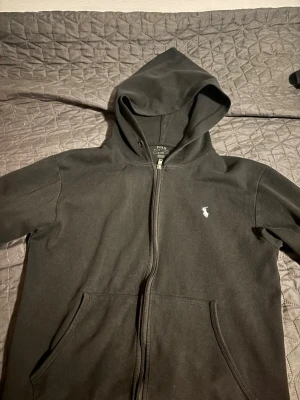 Svart hoodie från Polo Ralph Lauren - Säljer en svart hoodie från Polo Ralph Lauren med dragkedja framtill och klassisk huva. Pris kan diskuteras vid fler frågor hör av dig !