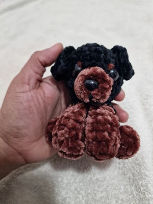 Handgjord virkad hund i plysch - Söt liten handgjord hund i mjuk plysch, virkad i svart och mörkbrunt garn. Har stora svarta plastögon och nos. Perfekt som prydnad eller gosedjur. Unik och charmig design som passar som present eller dekoration.