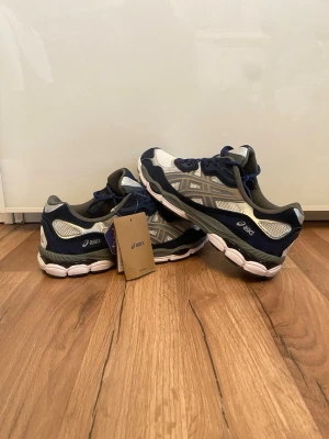 Asics new geal - Säljer ett par ASICS sneakers (New Gel-modell) i storlek 45. Sköna och stabila skor med bra dämpning – passar perfekt både till vardag och längre promenader.  • Storlek: 45 • Skick: Nya med tags • Färg: Blå/Grå • Bekväm GEL-dämpning • Original