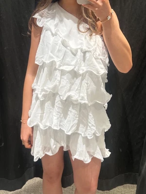 Vit volangklänning med ärmlös design - Supersöt vit klänning med flera lager volang perfekt för student eller skolavslutning. Storlek 164 men passar mig perfekt som är 165cm. Prislappen är kvar 