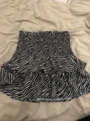 🖤trendig zebramönstrad kjol - superfin passform 🖤 -   Säljer en svartvit kjol med zebramönster och volang nertill 🌪️ Resår i midjan som sitter jättefint och är både bekväm och smickrande. Kjolen faller snyggt och funkar lika bra till vardag som till fest ✨  Perfekt att styla med en vit topp, svart linne eller oversized tröja. Riktigt trendig och svår att hitta – säljs pga används för sällan 🥲  📌 Skick: mycket bra 📌 Passform: stretch i midjan 📌 Stil: trendig / Y2K / somrig  Snabb affär uppskattas 💌   skickar dagen du köper eller dagen efter 💕