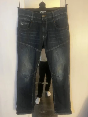 Mörkblå jeans från Pearson - Snygga mörkblå jeans från Pearson med coola sömdetaljer över benen och klassisk femficksdesign. Jeansen har en något tvättad look och gult kontrastsömnad vid knappen. Perfekta för en trendig och avslappnad stil. Hör av er vid frågor! W32 L32
