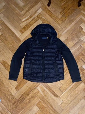 Svart cardigan  från Polo Ralph Lauren - Snygg svart cardigan från Polo Ralph Lauren med huva och dragkedja framtill. Jackan är i bra skicka Perfekt för kalla vinterdagar  eller nu till våren och riktigt stilren look. Den är svart!!