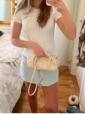 Ljusblåa denimshorts i bomull - Säljer ett par ljusblåa denimshorts i bomull med normal passform. Klassisk femficksmodell och avslappnad look, perfekta för varma dagar. Shortsen har dragkedja och knapp framtill.