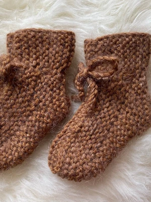 Stickade babystrumpor  - Supersöta babystrumpor stickade i merinoull, mohair och silke i storlek 0-3 månader. Går att knyta runt benen så att de sitter kvar😊.