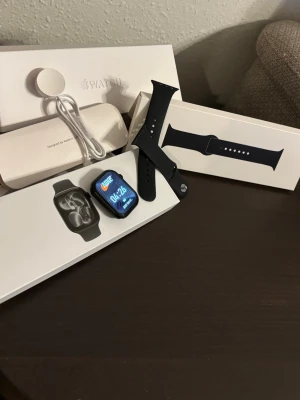 Apple Watch Nike svart aluminium - Apple Watch Nike med svart aluminiumboett och svart silikonarmband. Klockan har en fyrkantig form, färgskärm och Nike-logga på urtavlan. Medföljer laddkabel och originalförpackning. Perfekt för dig som gillar sportig design och smarta funktioner.