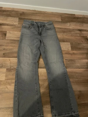 Flared jeans  - Säljer ett par gråa jeans från Zara med utsvängda ben och klassisk femficksmodell. Jeansen har hög midja och är tillverkade i bomull med en snygg tvättad finish. Perfekta för en trendig och avslappnad look.