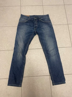 Blå raka jeans från dondup - Snygga blå jeans från dondup med klassisk femficksmodell och raka ben. Jeansen har en lätt tvättad look med subtila slitningar och kontrastsömmar. Perfekta för en avslappnad och trendig stil.