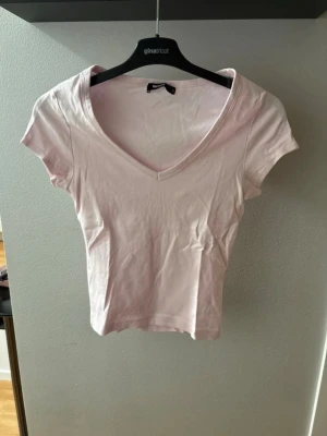 Ljusrosa v-ringad topp från Bik Bok - Säljer en ljusrosa topp från Bik Bok med v-ringning och korta ärmar. Toppen är lite croppad och har en enkel, stilren design i mjuk bomull men lite heavy material. 