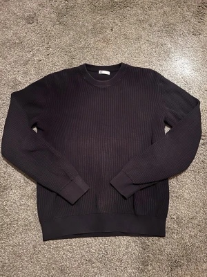 Marinblå ribbad tröja från Cubus - Snygg marinblå ribbad tröja från Cubus med rund halsringning och långa ärmar. Tröjan har en stilren och enkel design med breda muddar vid ärmslut och nederkant. Perfekt för dig som gillar minimalistisk stil.