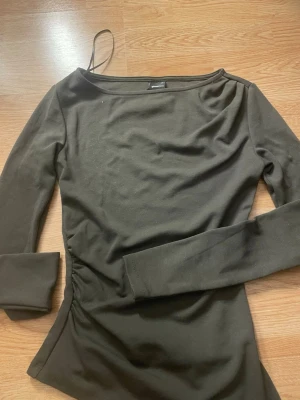 Mörkgrön långärmad topp Gina Tricot - Snygg mörkgrön långärmad topp från Gina Tricot. Modellen har en enkel, stilren design med rundad halsringning och figurnära passform. Perfekt att matcha med jeans eller kjol för en trendig look. Använd nån enstaka gång.