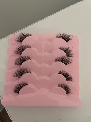 Fem par volymfransar i svart - Säljer ett set med fem par svarta volymfransar i en rosa plastförpackning. Fransarna har en fyllig och böjd design som ger en dramatisk look till ögonen. Perfekt för dig som vill ha extra långa och täta fransar. Lätta att applicera och passar till många olika sminkningar.