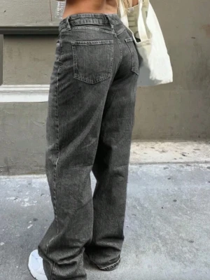 Gråa loose fit jeans - Säljer ett par gråa loose fit jeans med raka ben. Jeansen har klassiska fem fickor och silverfärgade detaljer vid knappar och dragkedja. 