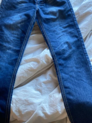 Blå raka jeans med kontrastsömmar - Snygga blå jeans med raka ben och tydliga kontrastsömmar. Klassisk femficksmodell med normalhög midja och lätt tvättad look. Perfekta för en avslappnad stil och passar till det mesta. Materialet är denim i bomull.