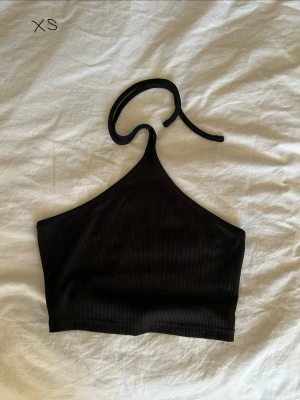 Svart ribbad halterneck topp - Hej! Säljer en svart ribbad halterneck topp med knyt i nacken. Den är från SHEIN